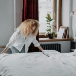 photo of woman in white long sleeve shirt cleaning bed